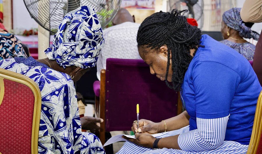Mercy Hands volunteer helping an elderly woman fill out a form